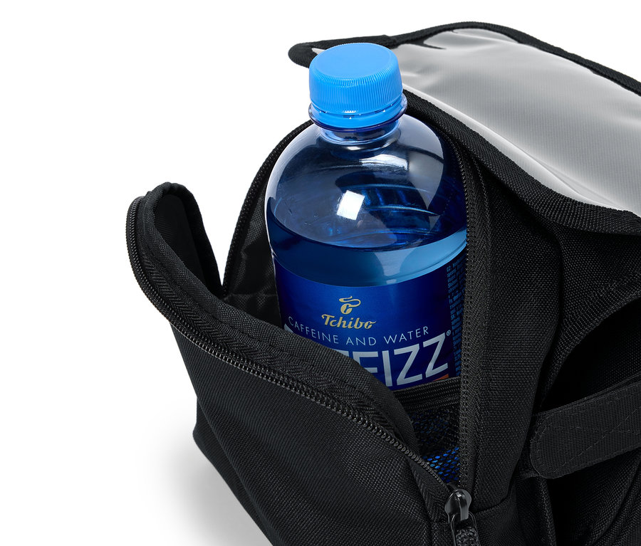 V otevřené černé tašce je umístěna modrá láhev Tchibo Caffeine and Water Fizz.