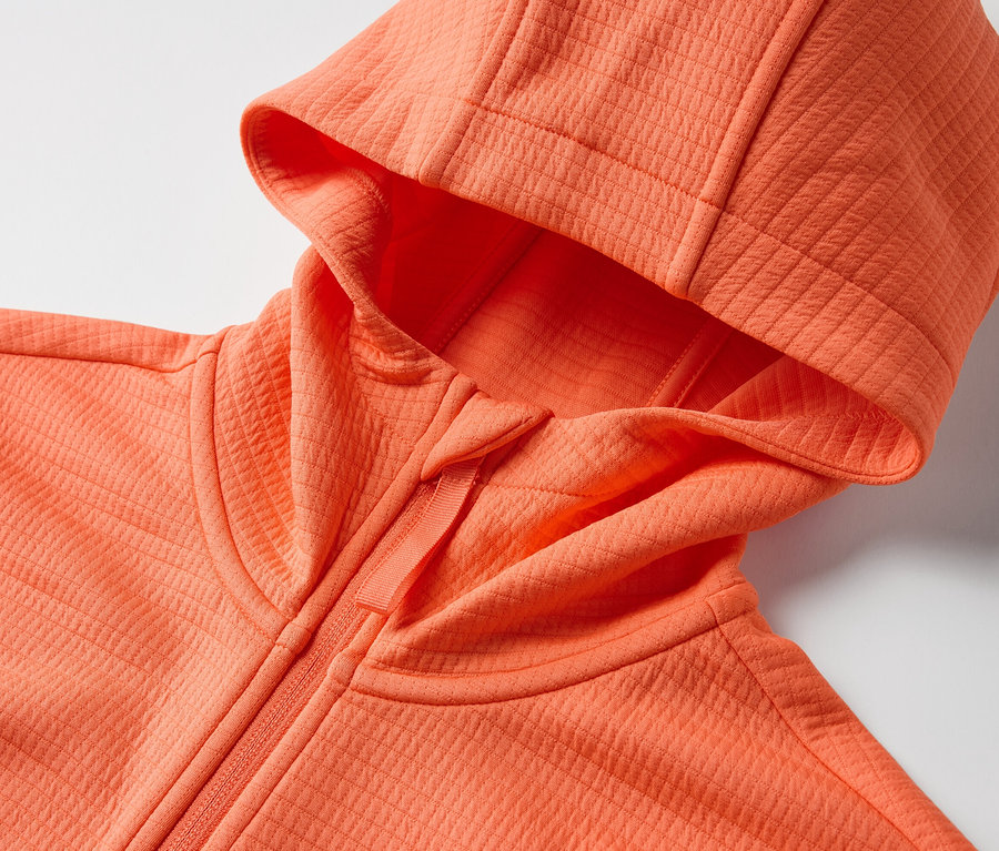 Detail oranžové funkční bundy s kapucí.