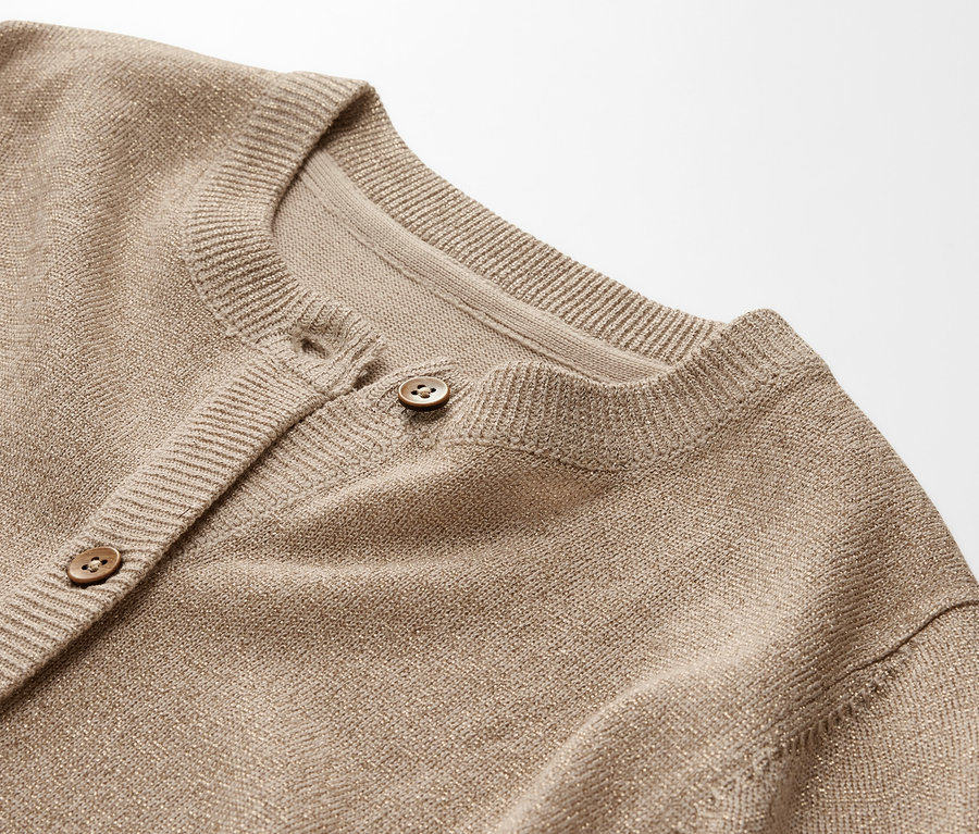 Detail dětského svetru z lesklého úpletu s knoflíky.