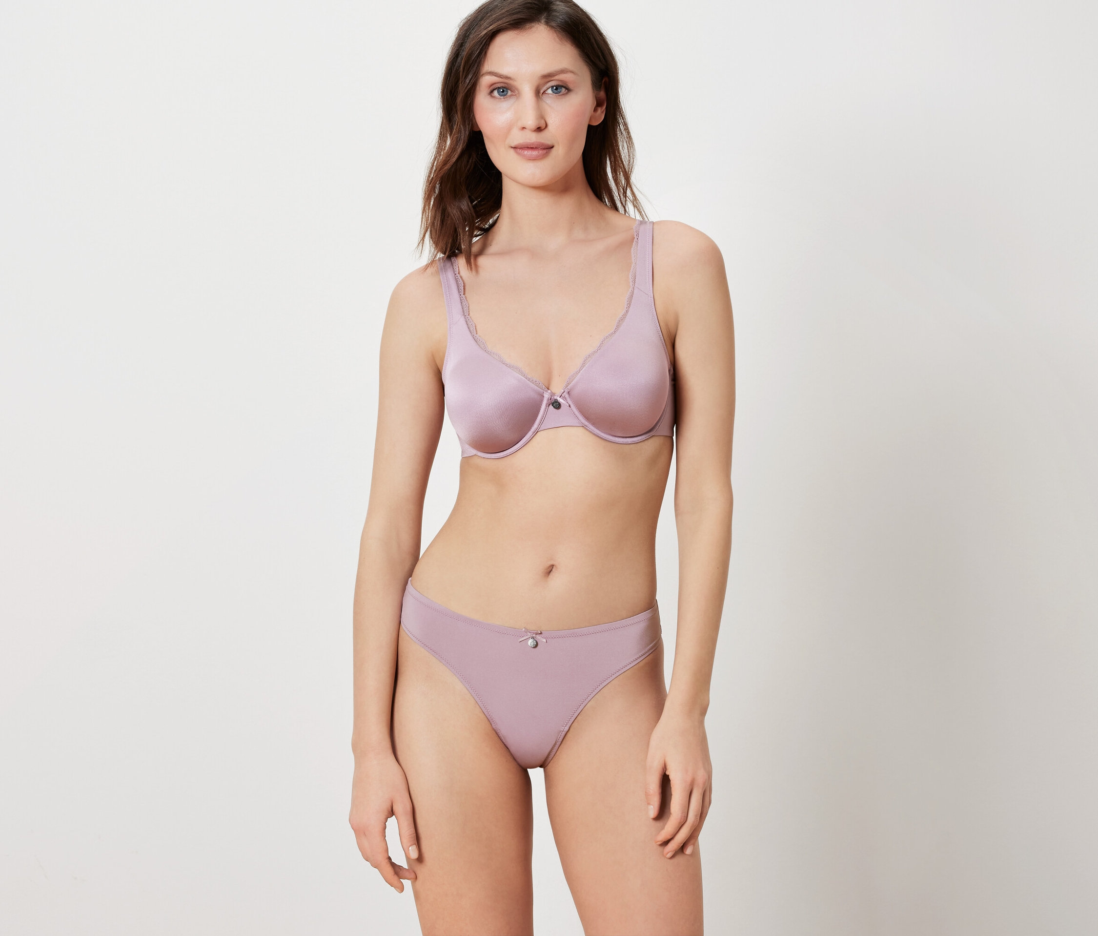 Žena pózuje na bílém pozadí v odpovídající fialové podprsence a kalhotkách.