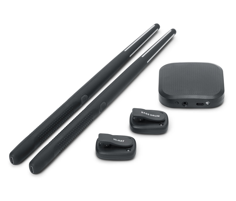 Dvě černé paličky na bicí leží vedle sebe. K dispozici je také černá zvuková skříňka a dvě malé černé bicí podložky, jedna s nápisem BASS DRUM a druhá s nápisem HI-HAT.