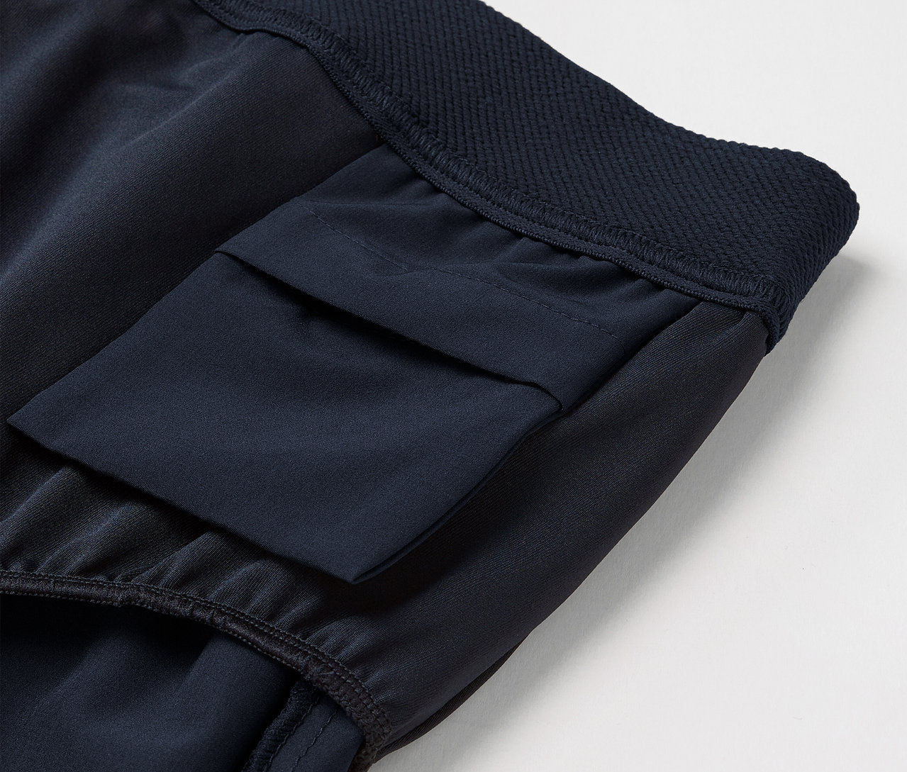 Detail tmavě modrých šortek s kapsou.