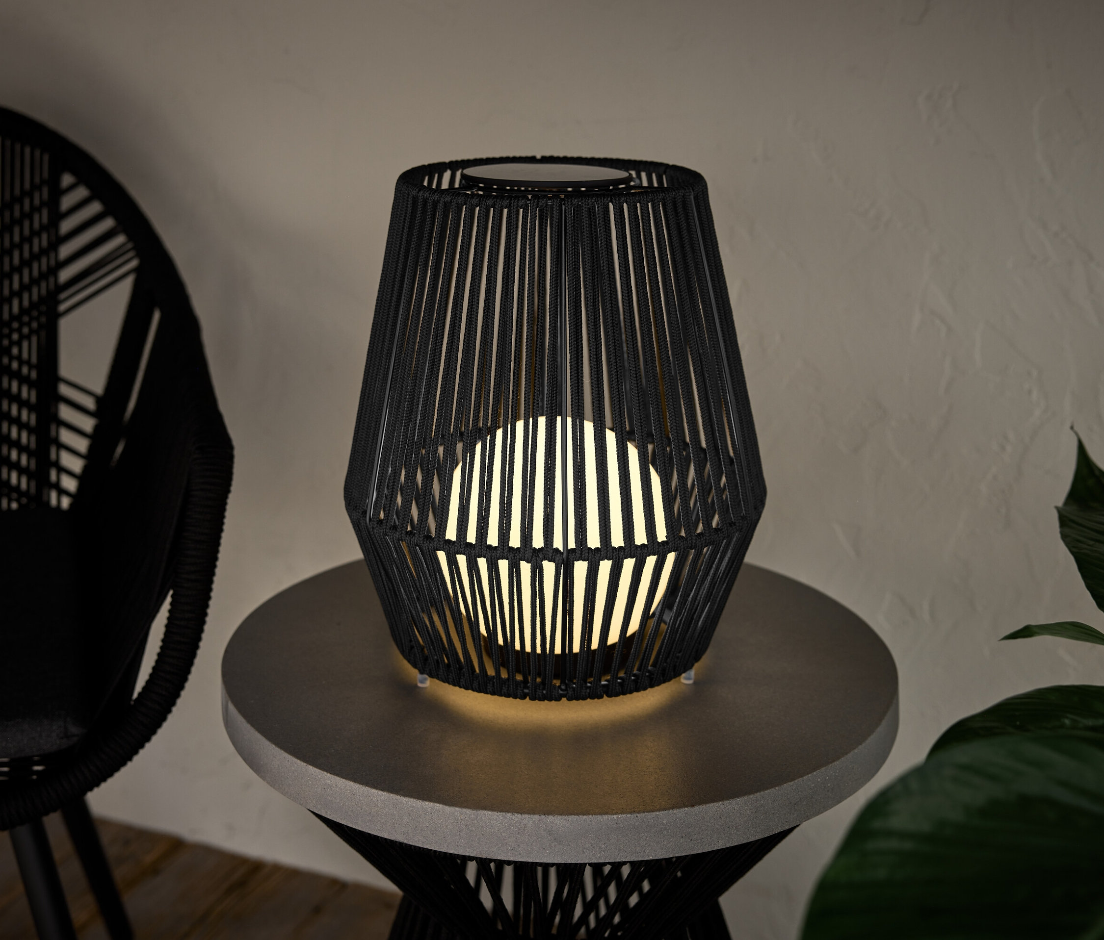 Malá solární lucerna s textilním výpletem stojí na stolku.