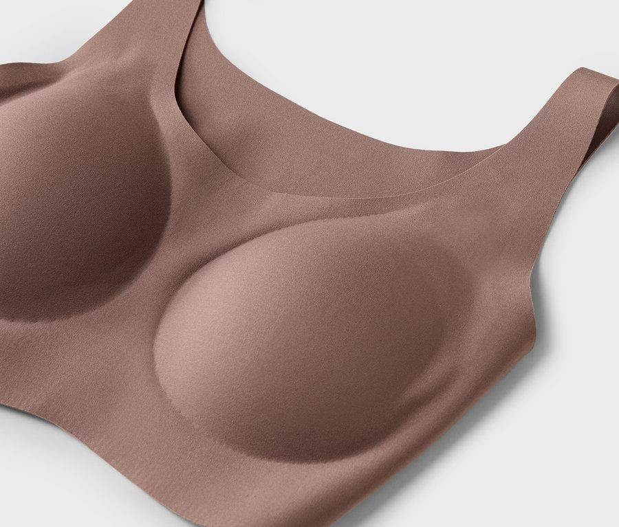 Detail béžové podprsenky s tvarovanými košíčky na bílém pozadí.