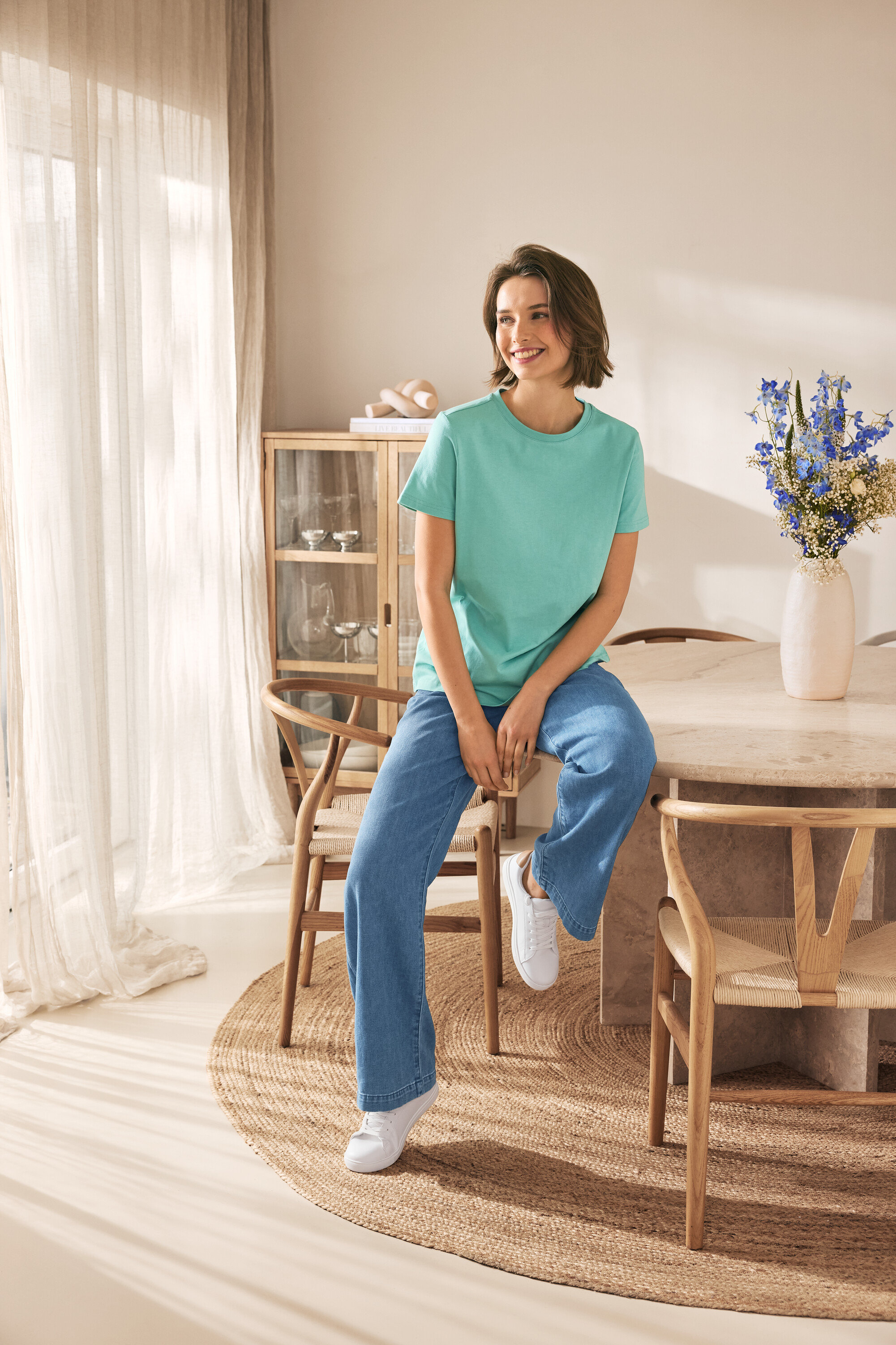 Žena sedí na židli a má na sobě kožené tenisky.