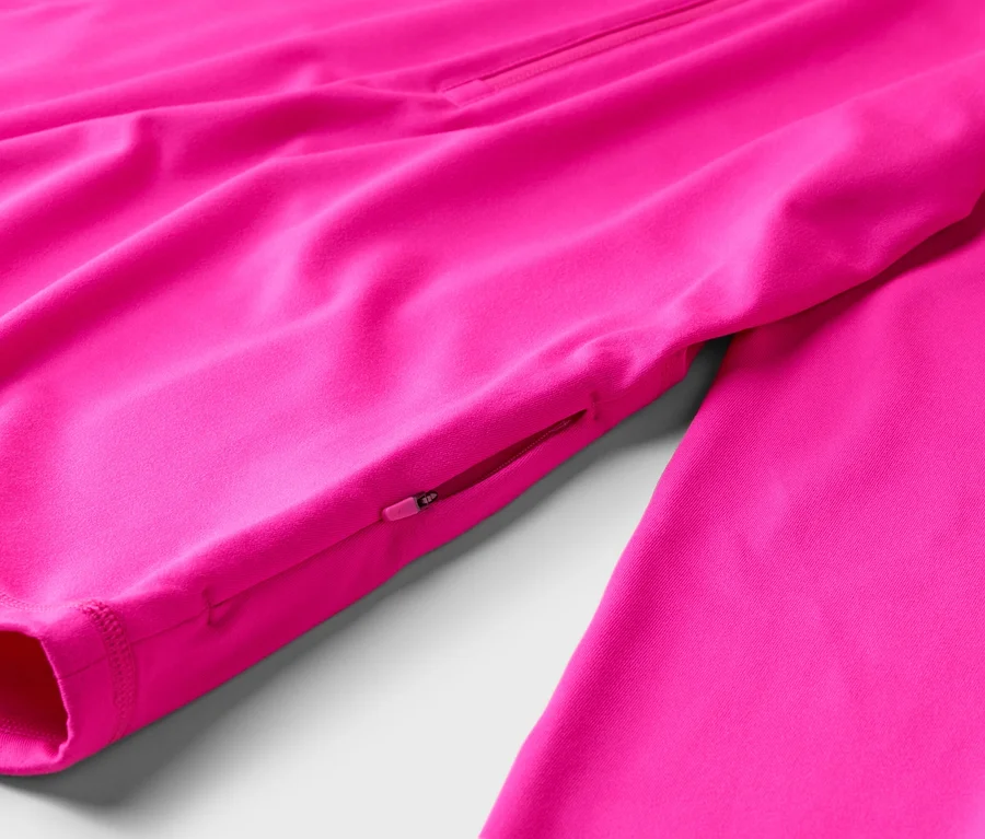 Detail růžové bundy s kapsou na zip na rukávu.