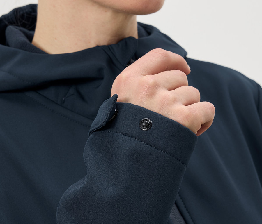 Detailní záběr osoby zapínající patentku na manžetě tmavě modré bundy.