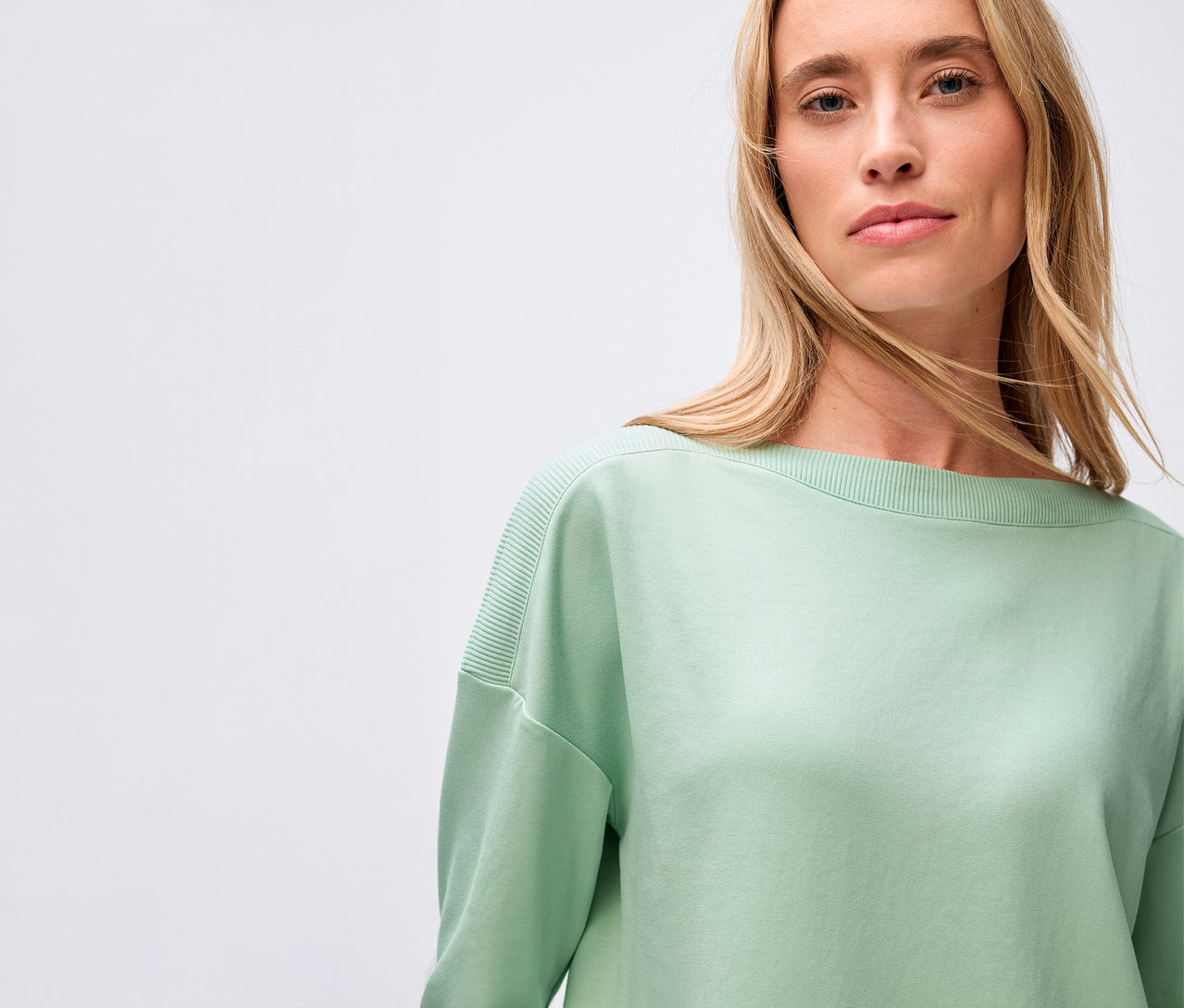 Žena má na sobě šalvějově zelené tričko Street One s žebrovaným detailem.