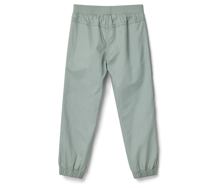 Světlé kalhoty s elastickým pasem a manžetami na kotnících, focené zezadu.