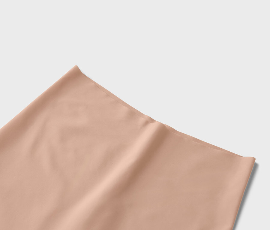 Detailní záběr jednobarevné látky v broskvové barvě.