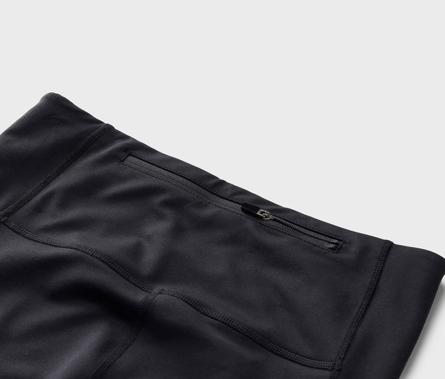 Detailní záběr na černé legíny s kapsou na zip.