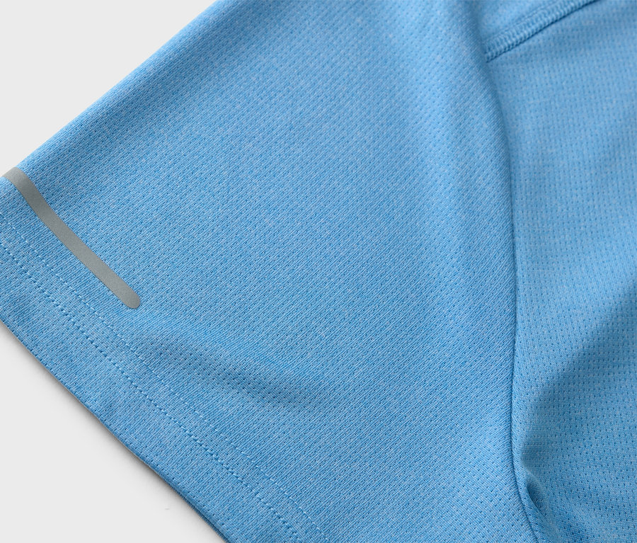 Detailní záběr na světle modré sportovní tričko s reflexním pruhem na rukávu.