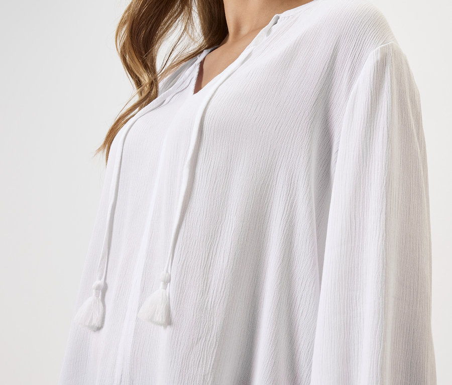 Detailní záběr ženy v bílé blůze se stahovací šňůrkou.