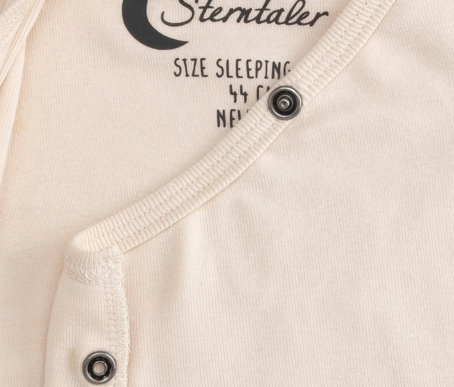 Detail krémového vnitřního spacího pytle pro miminka Sterntaler s patentkami a částečně viditelným textem „SIZE SLEEPING“.