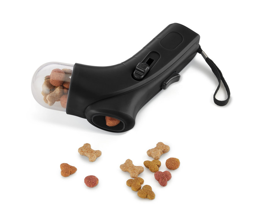 Černý zásobník metající pamlsky se zásobníkem plným pamlsků a pamlsky rozsypanými pod ním.