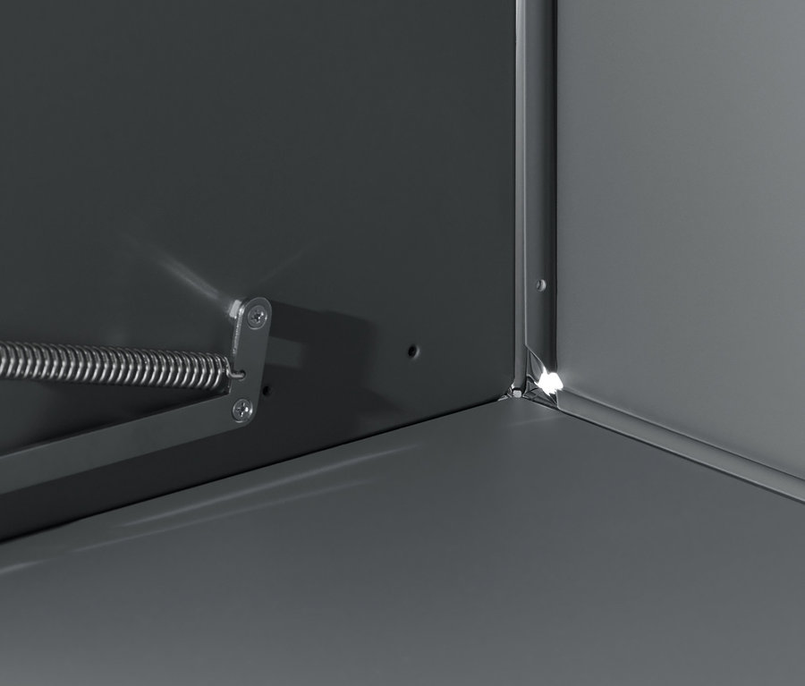 Detail šedé odkládací skříňky CN3 s výklopnými dvířky a kovovým mechanismem.