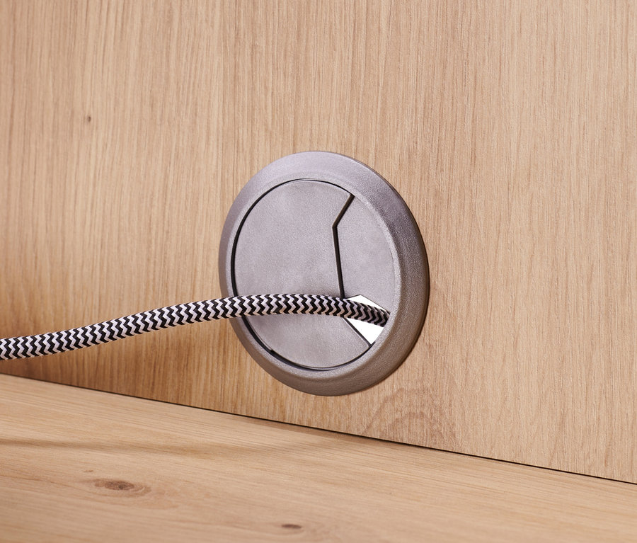 Detail komody se zásuvkami a dvířky, kabel protažený otvorem.