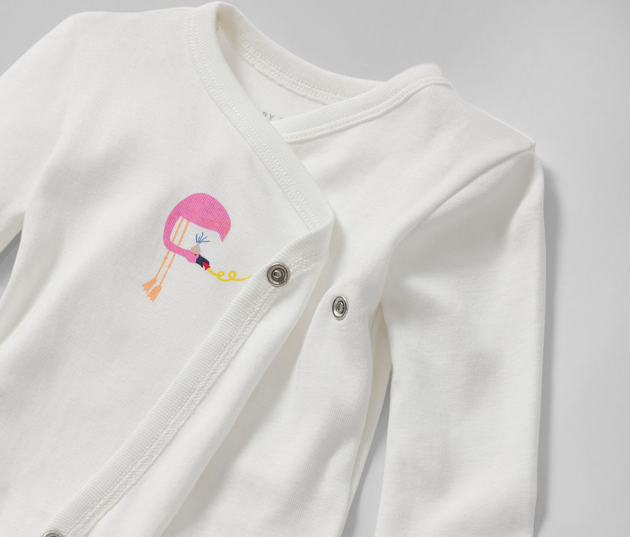 Detail bílého rostoucího body pro miminka s výšivkou plameňáka.