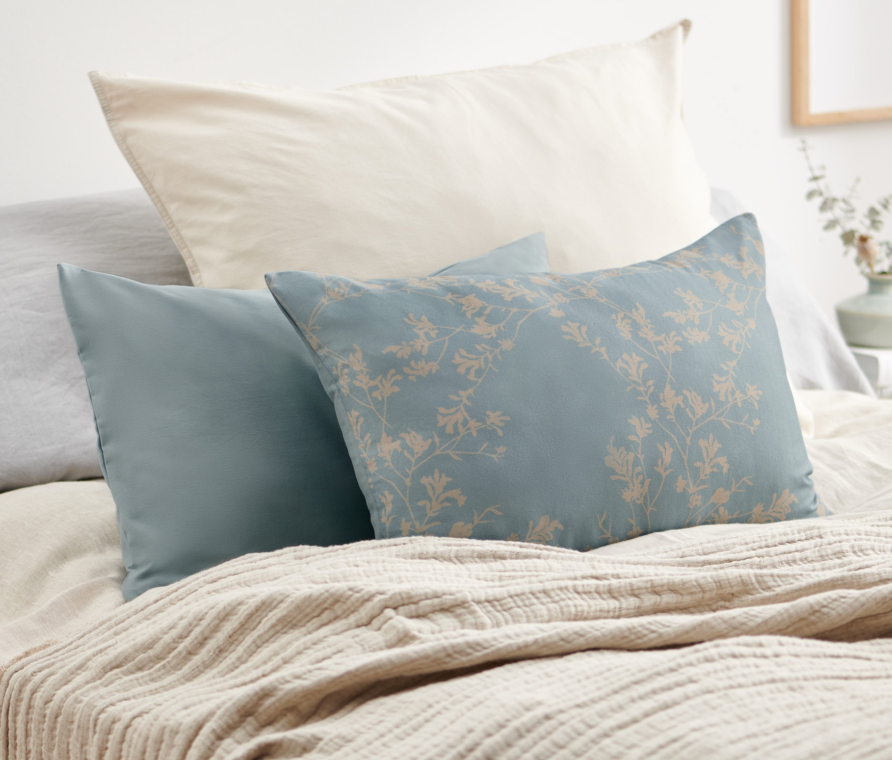 Dva povlaky na dekorační polštářky leží na posteli.