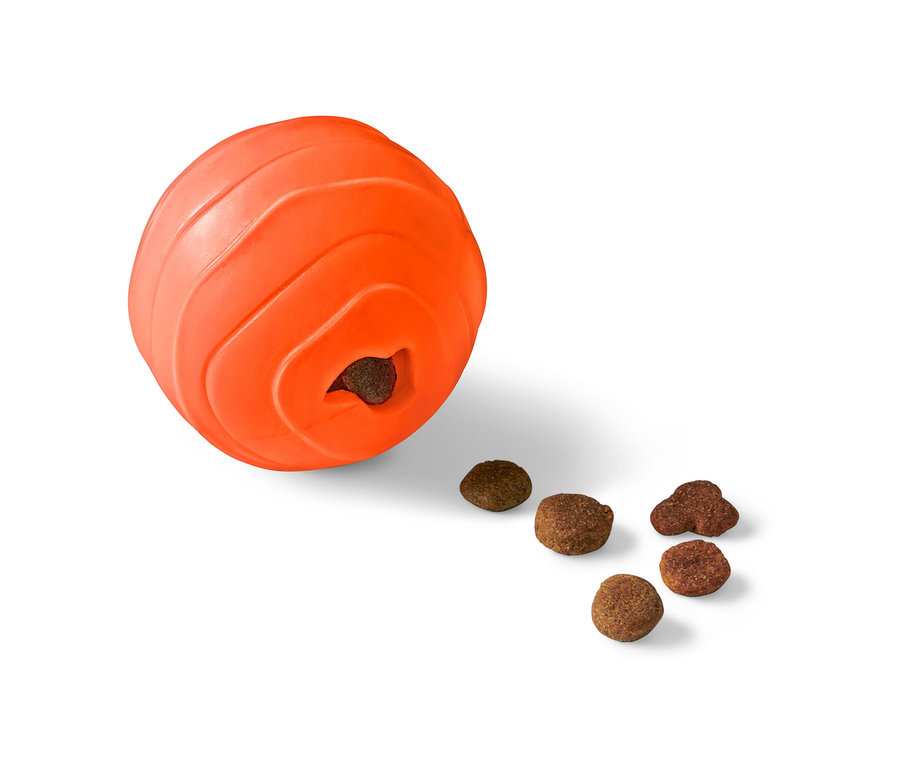 Oranžový snackball pro psy s otvorem, ze kterého vypadávají granule.