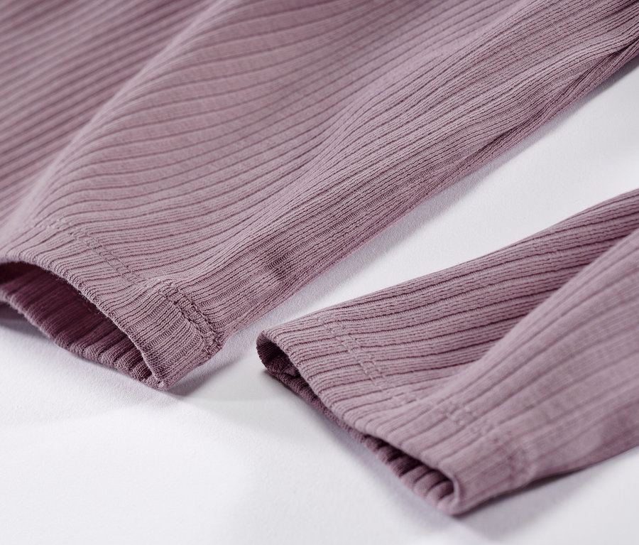 Detail dětského trika s dlouhým rukávem a žebrovanou strukturou.