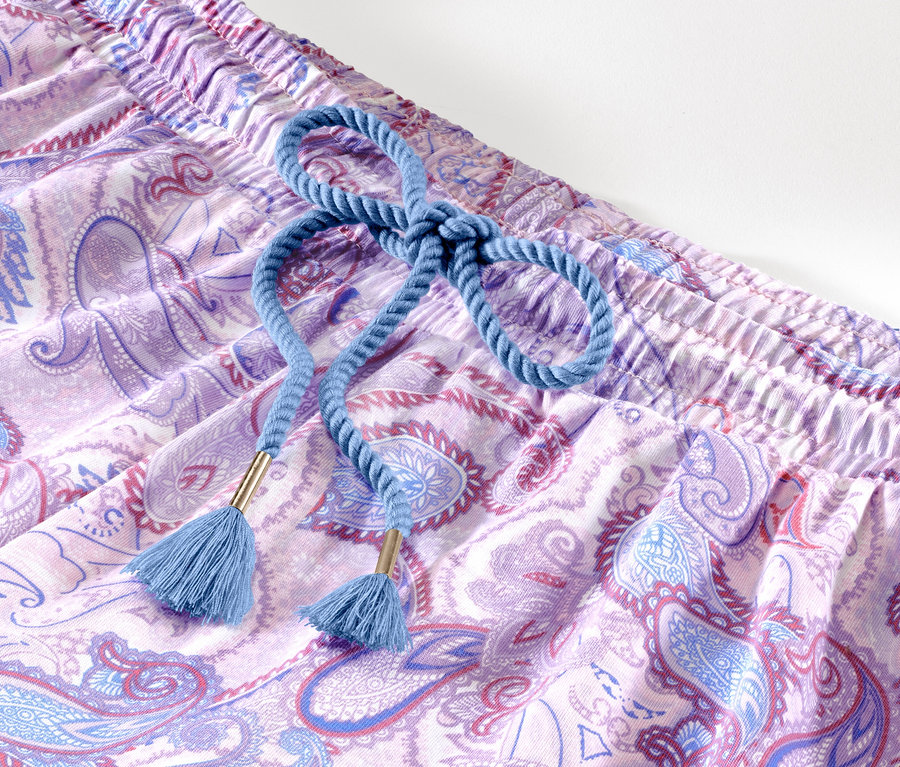 Detail krátké pyžamové soupravy s fialovým paisley vzorem a modrou šňůrkou.