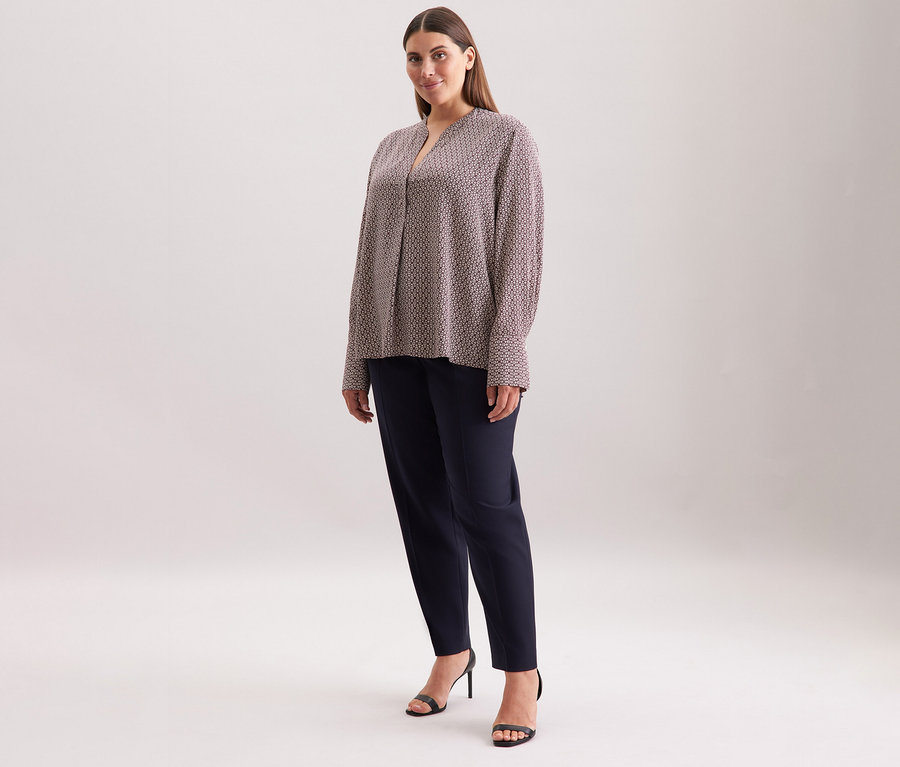 Žena má na sobě tuniku z viskózy Seidensticker s celoplošným potiskem v ecru a burgundské barvě.