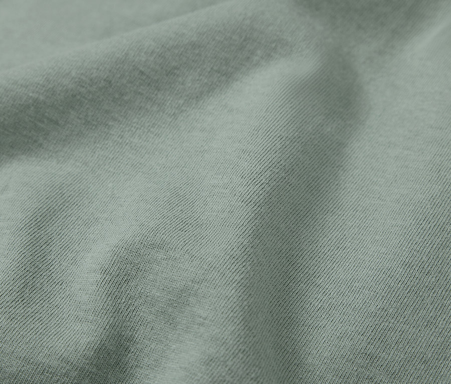 Detailní záběr na světle zelenou látku s diagonálním žebrováním.