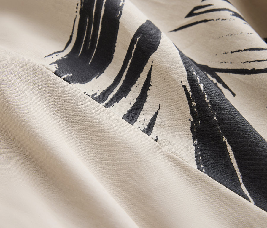 Detail krémové látky s tmavě modrým abstraktním potiskem.