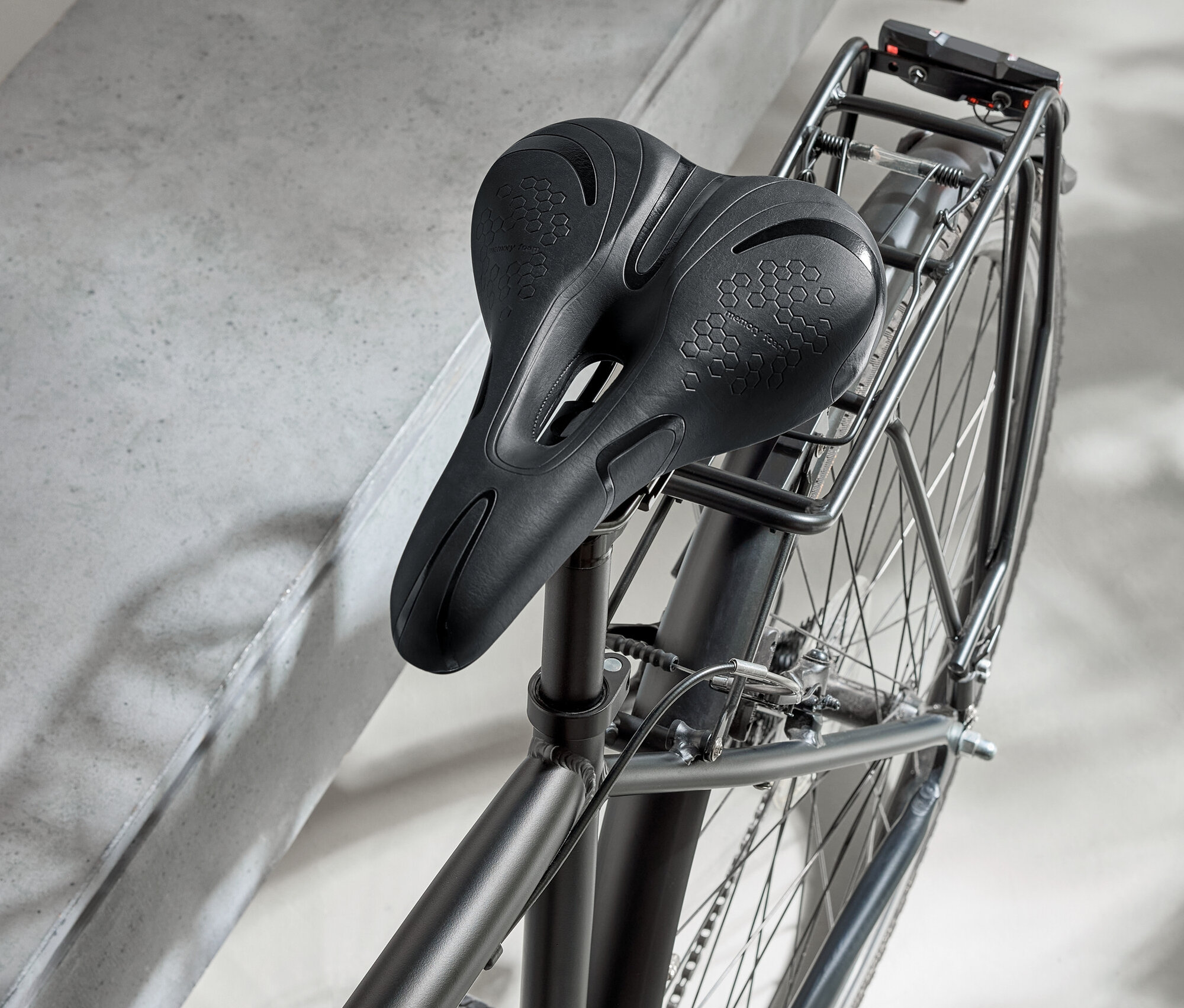 Černý bicykl s černým sedlem a černou helmou na betonovém povrchu.