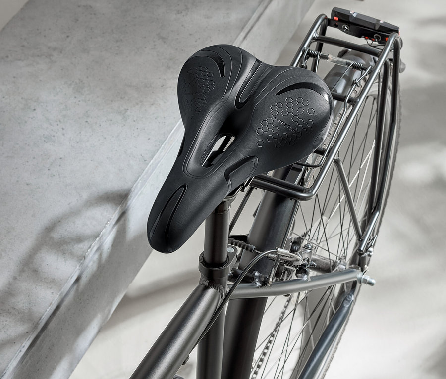 Černý bicykl s černým sedlem a černou helmou na betonovém povrchu.