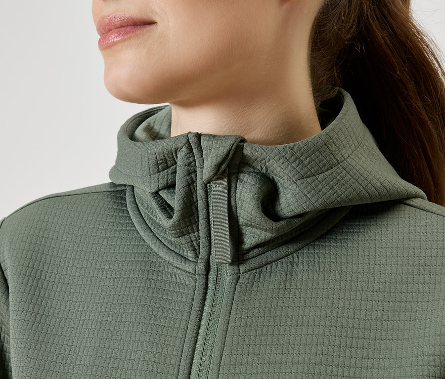 Detailní záběr ženy v zelené mikině s kapucí na zip.