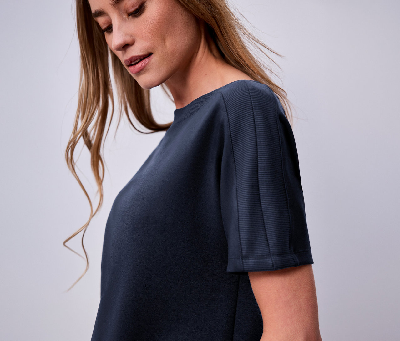 Žena má na sobě námořnicky modré tričko s krátkým rukávem Street One.