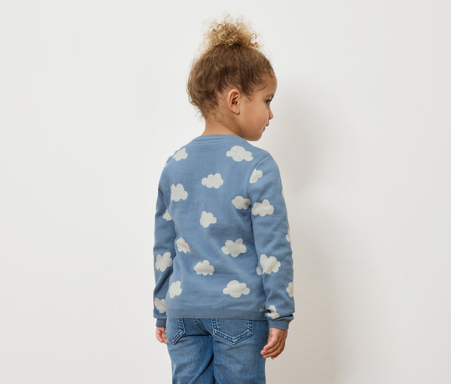 Dítě zezadu, má na sobě modrý svetr se vzorem mraků a džíny.