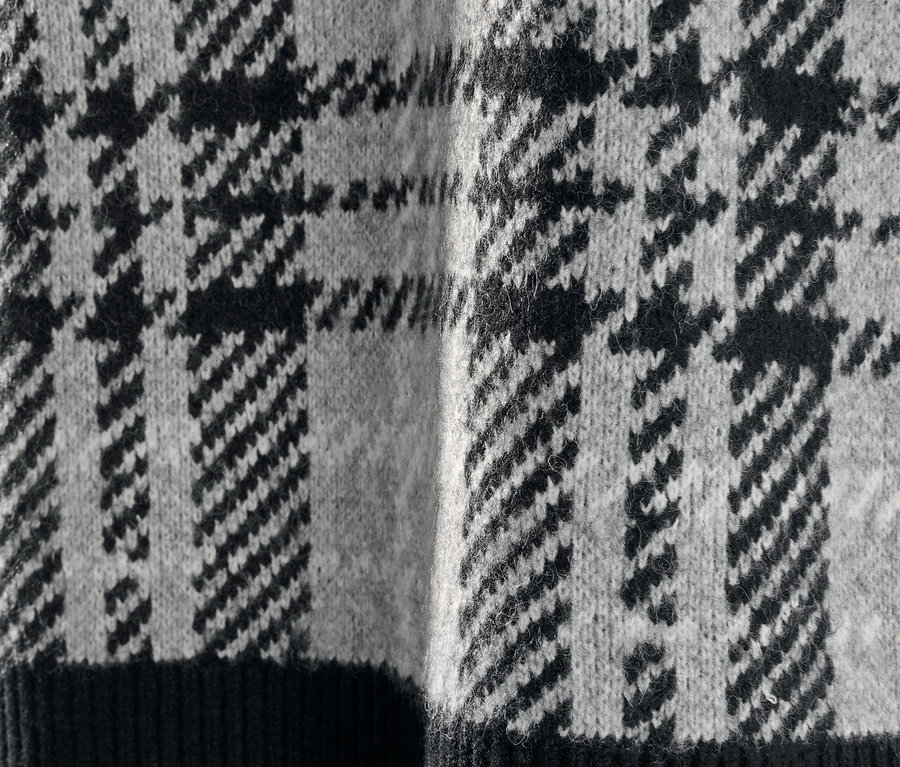 Detail pleteného svetru s kohoutí stopou.