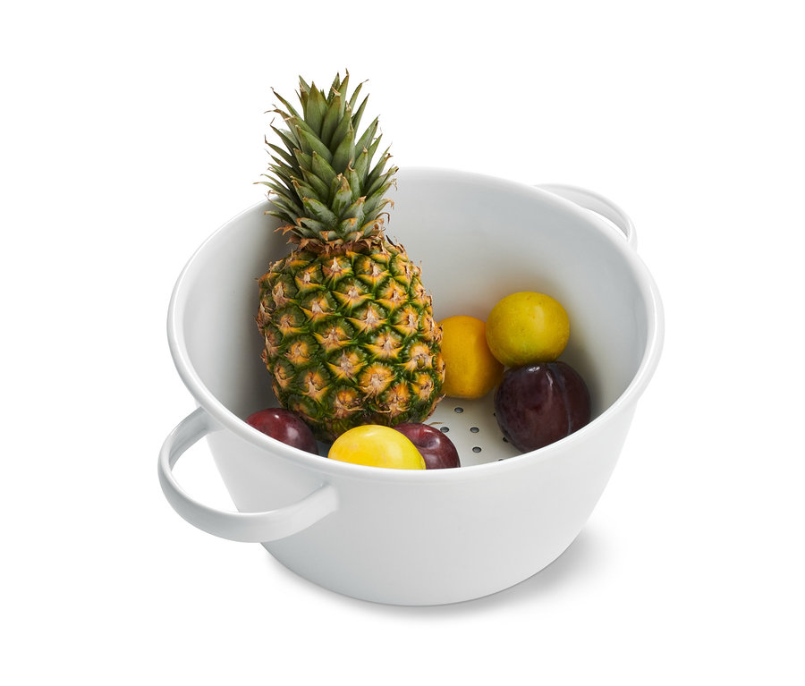 Ananas, švestky a citrony ve smaltovaném cedníku.