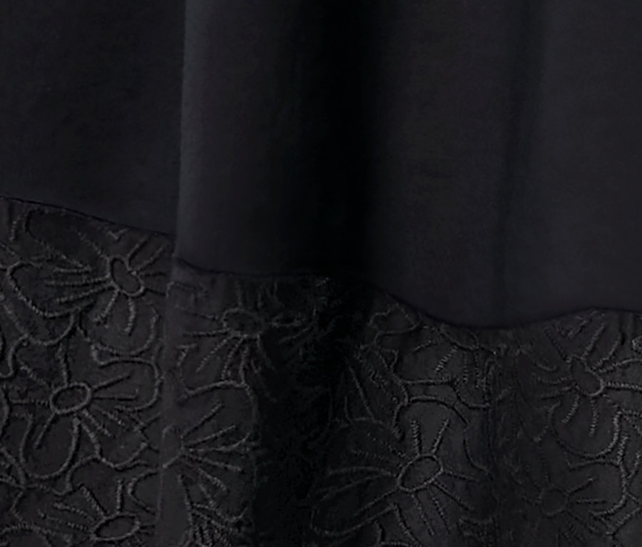 Detail tkaných šatů s výšivkou.