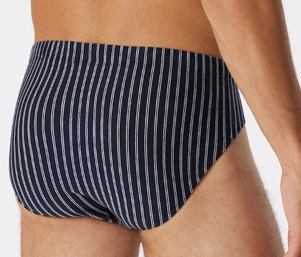 Muž má na sobě tmavě modré mini slipy SCHIESSER s bio bavlnou a svislými bílými proužky.