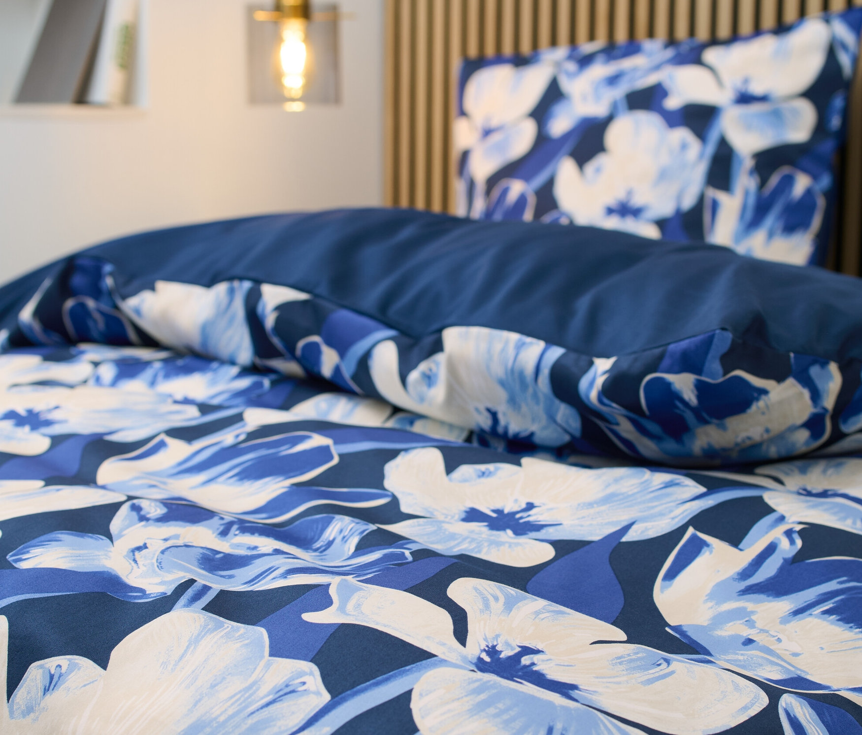 Detail saténového povlečení s květinovým vzorem standardní velikosti.