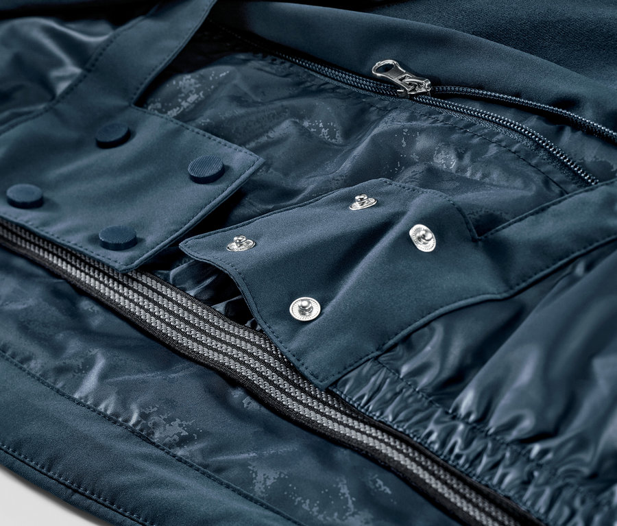 Detail námořnicky modré lyžařské bundy se zipem a knoflíky.