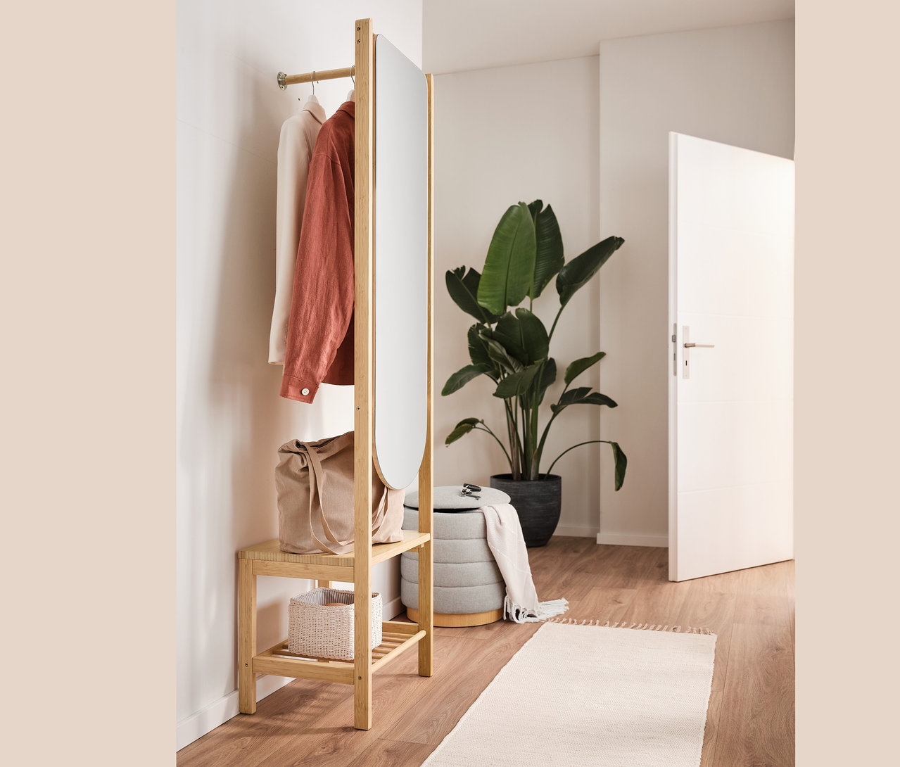 Otevřená šatní skříň se zrcadlem a odkládací plochou, puf s úložným prostorem, taška a oblečení v interiéru.