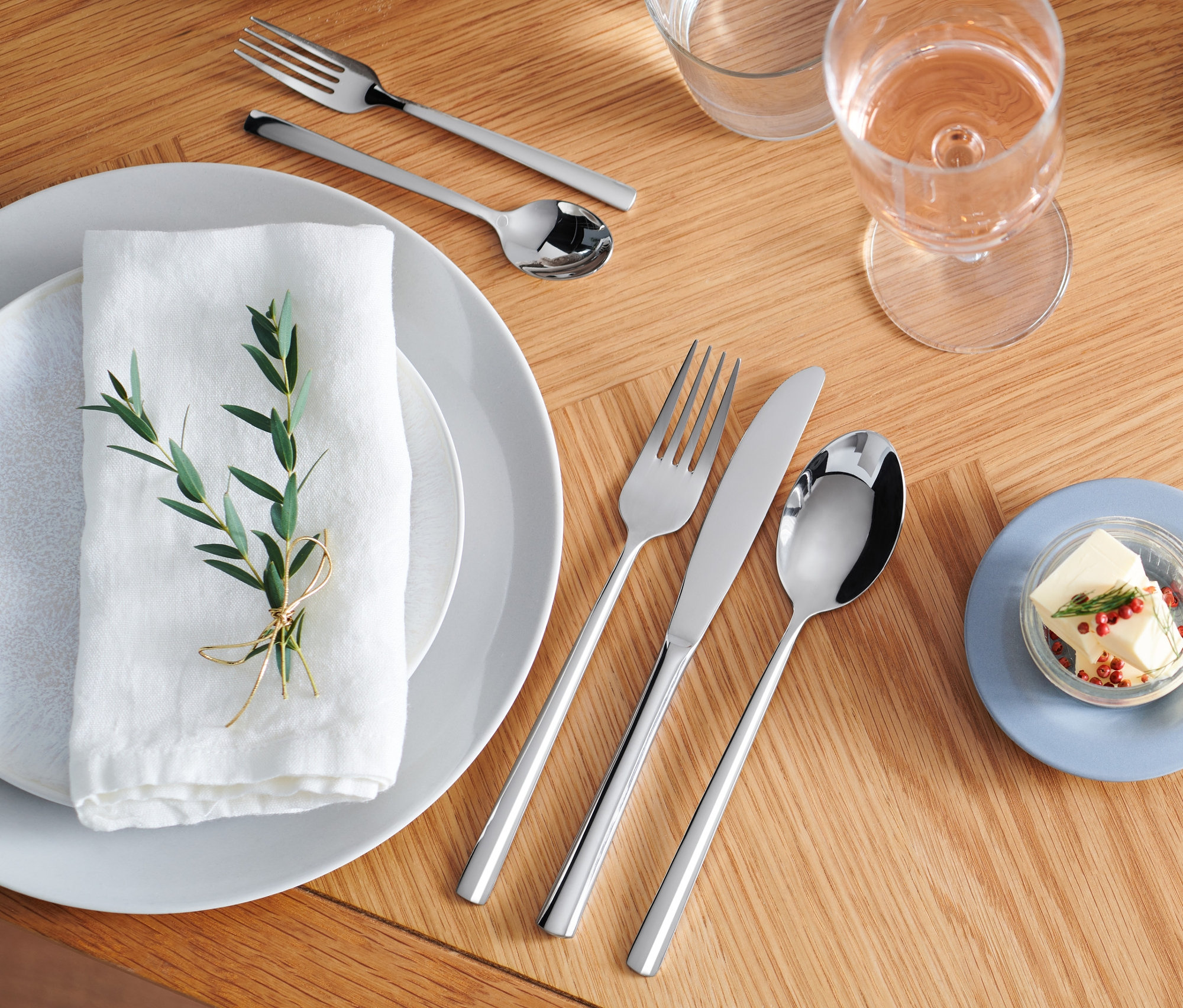 Sada příborů z nerezové oceli na dřevěném stole.