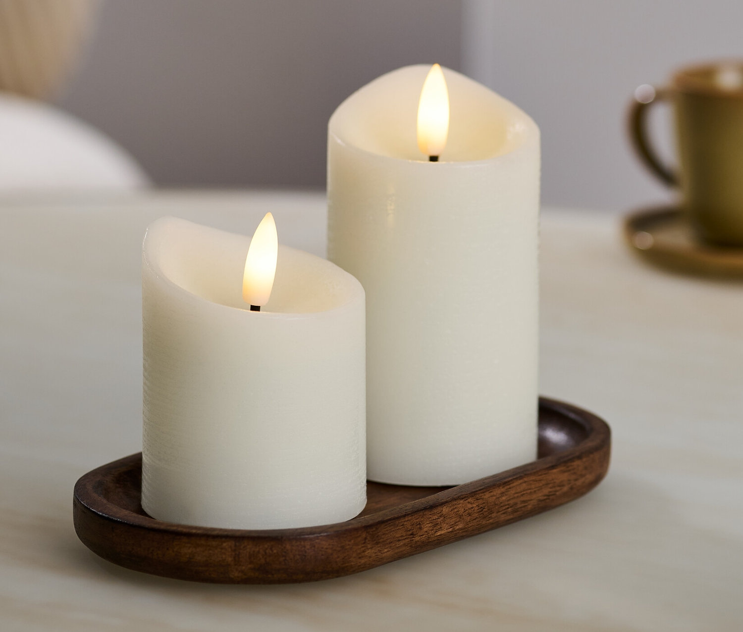 Dvě krémové LED svíčky z pravého vosku na hnědém podnose.