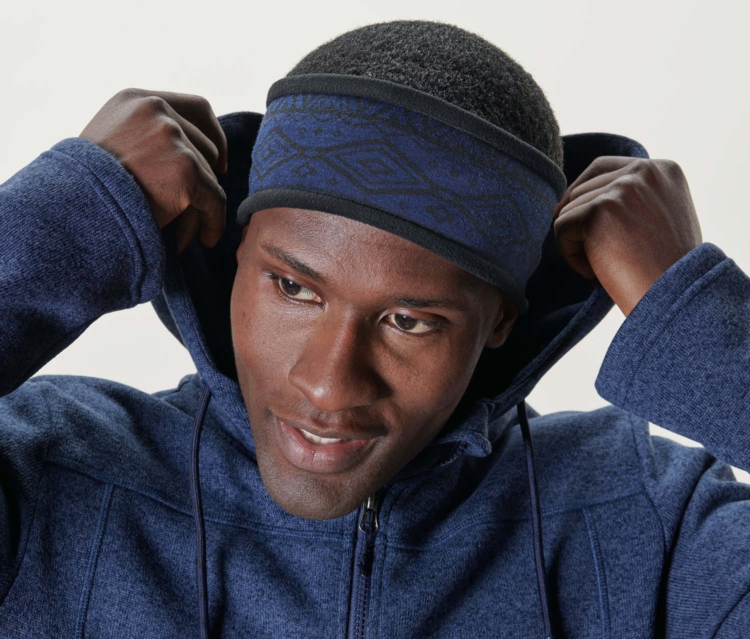 Muž si upravuje modrou fleecovou termo čelenku na hlavě.