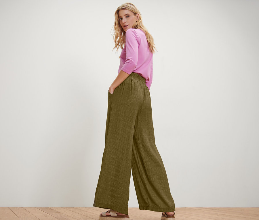 Žena pózuje v nazouvacích kalhotách a růžovém topu.
