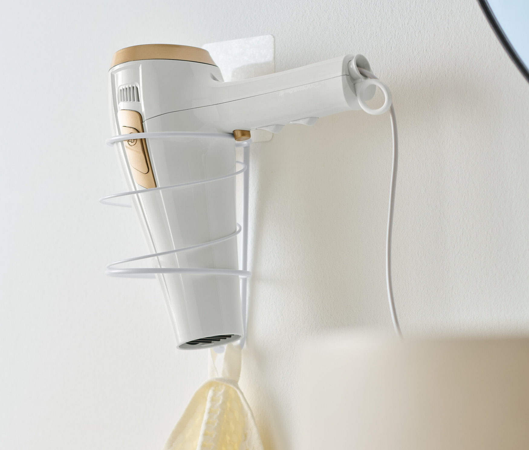 Bílý fén je umístěn v držáku na fén.