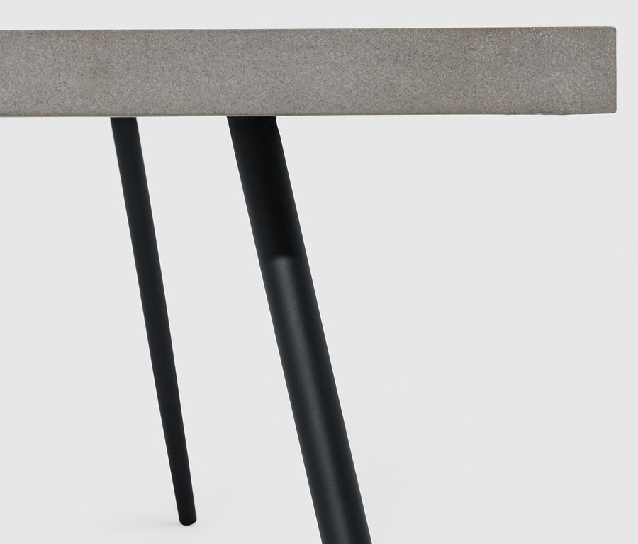 Detail konferenčního stolku s polycementovou deskou a černými nohami.