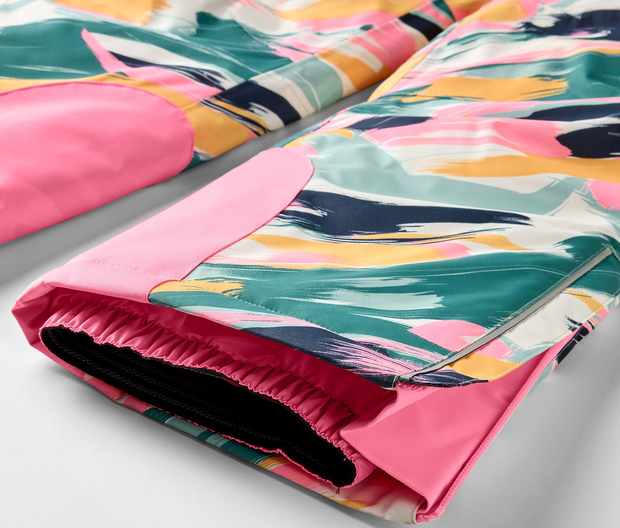 Detail pestrobarevných kalhot s růžovými detaily.