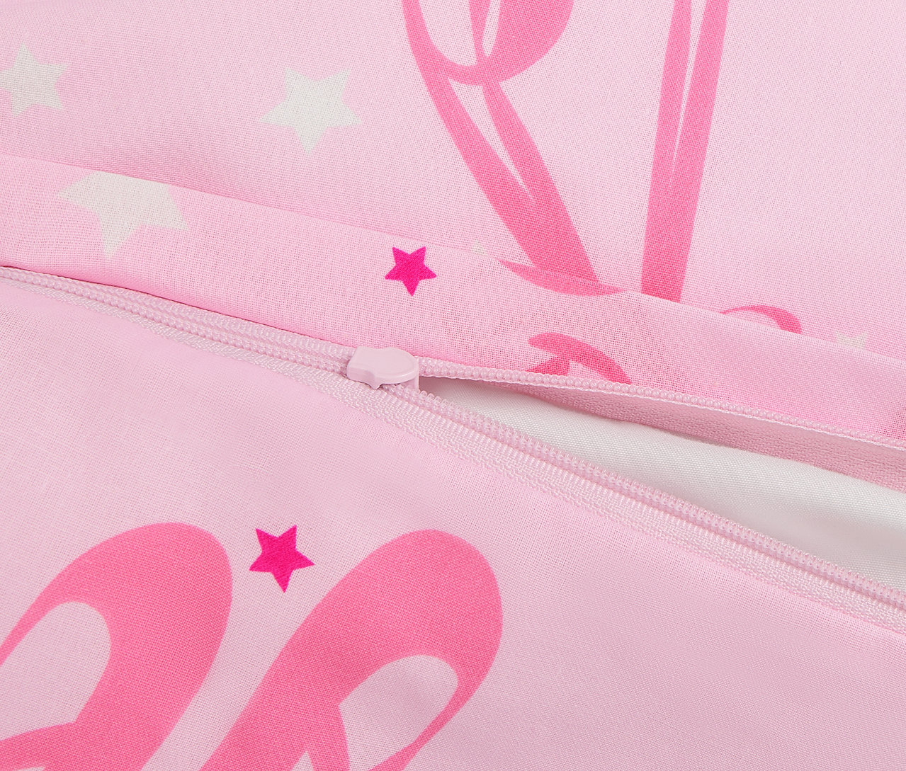 Detail růžového povlečení se zipem a potiskem hvězd a baletek.