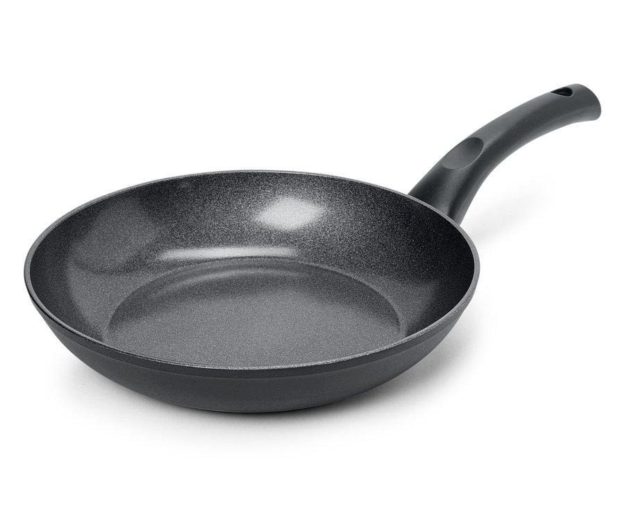 Detailní záběr na černou pánev s texturovaným povrchem na bílém pozadí.